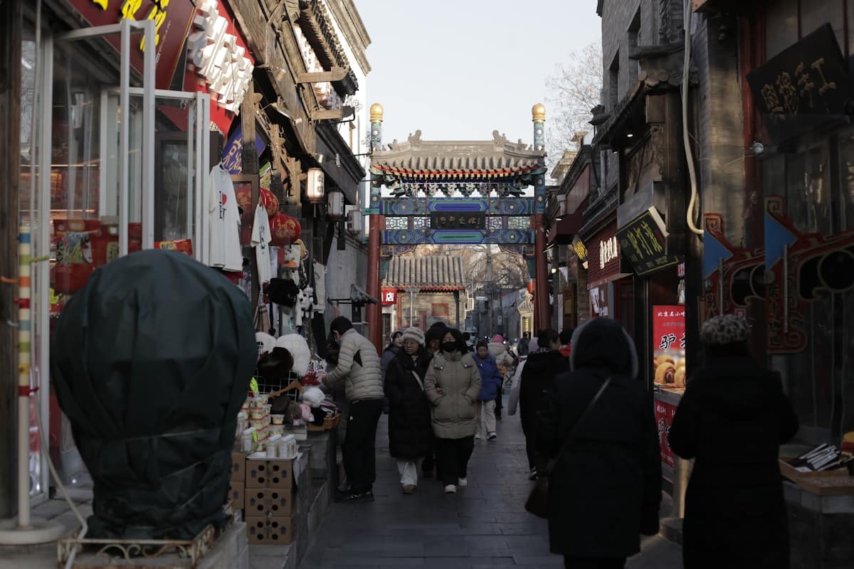 a week in beijing - narrow hutong alley lined with small shops and walking pedestrians