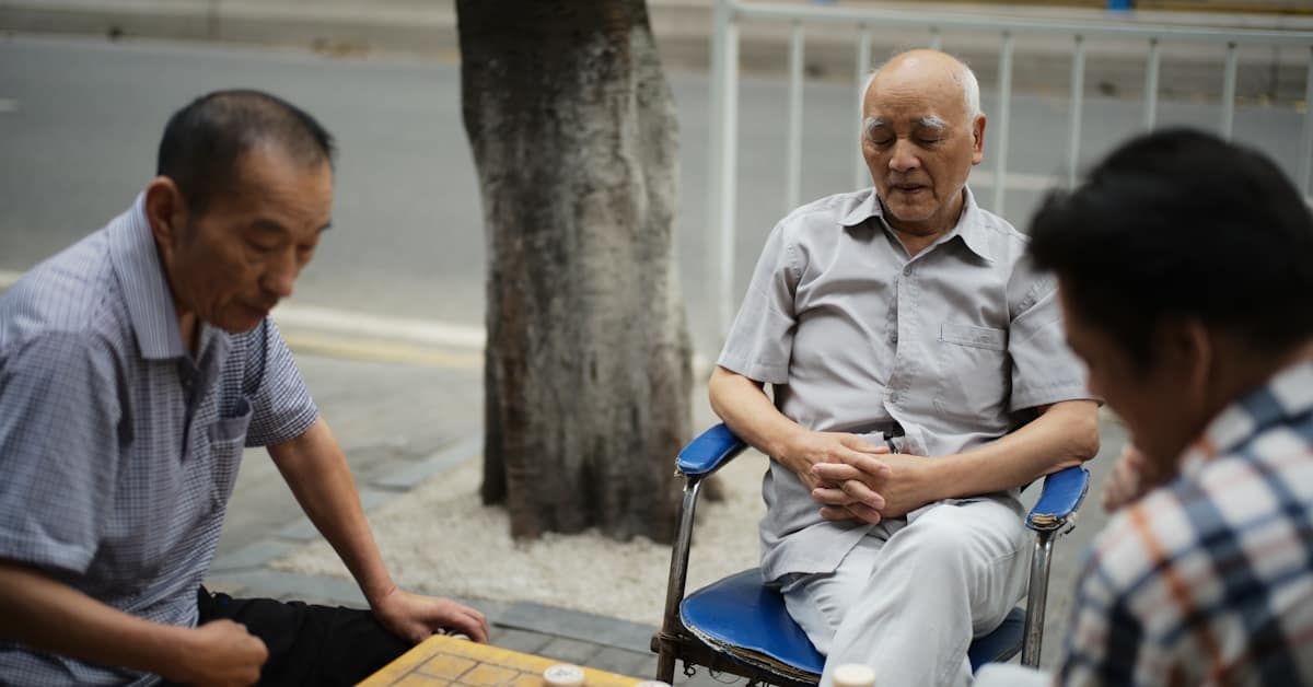 chinese park elderly - three elderly men playing a board game outdoors