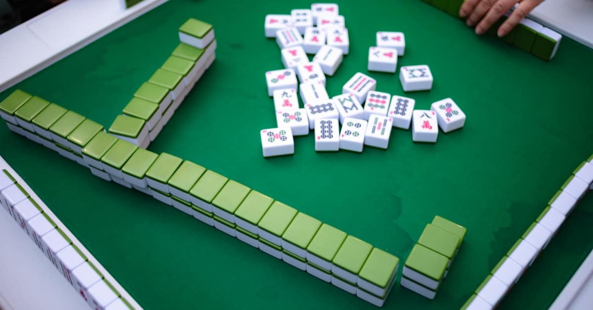 mahjong game - people playing mahjong around a green table