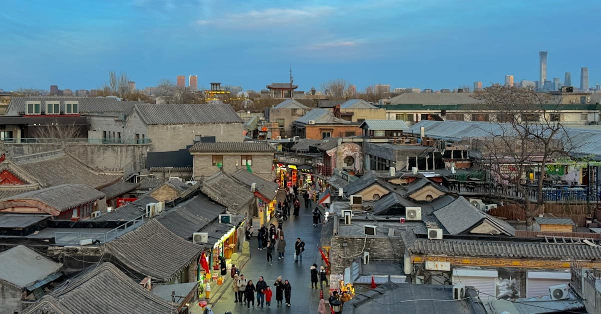 beijing first time - hutong alley at dusk with red lanterns and walking residents
