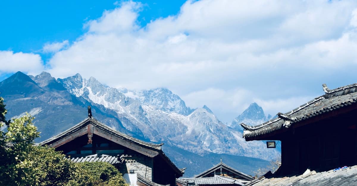 jiuzhaigou travel - tibetan buildings with snow mountains behind