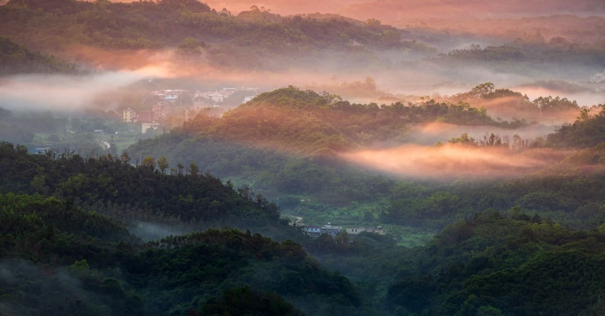 guizhou travel - misty mountains at sunrise with golden light