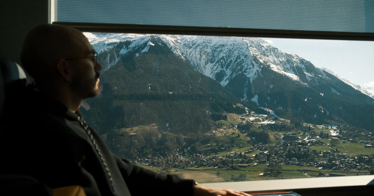 Passenger looking out train window at mountain scenery