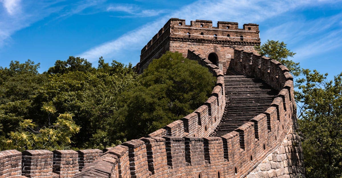 great wall china - restored wall section surrounded by lush green hills