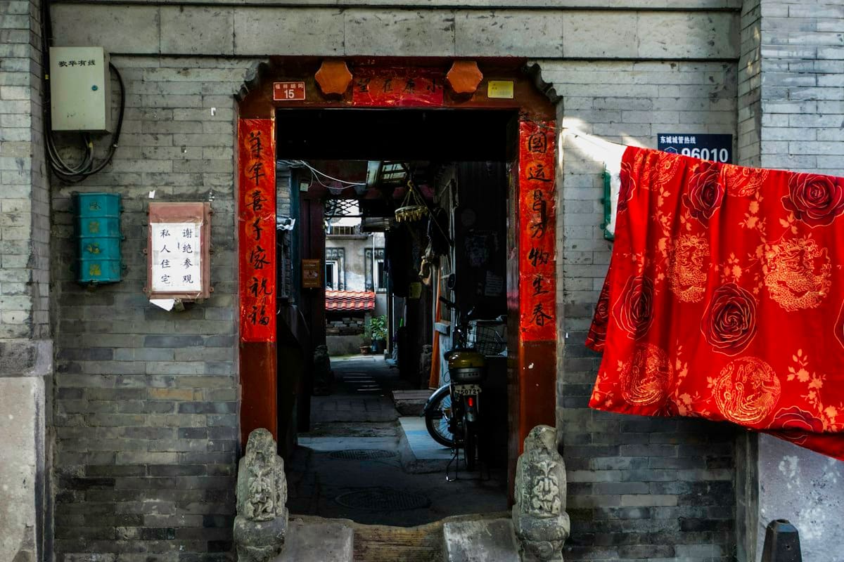 beijing hutong - red and white textile on brown wooden courtyard door