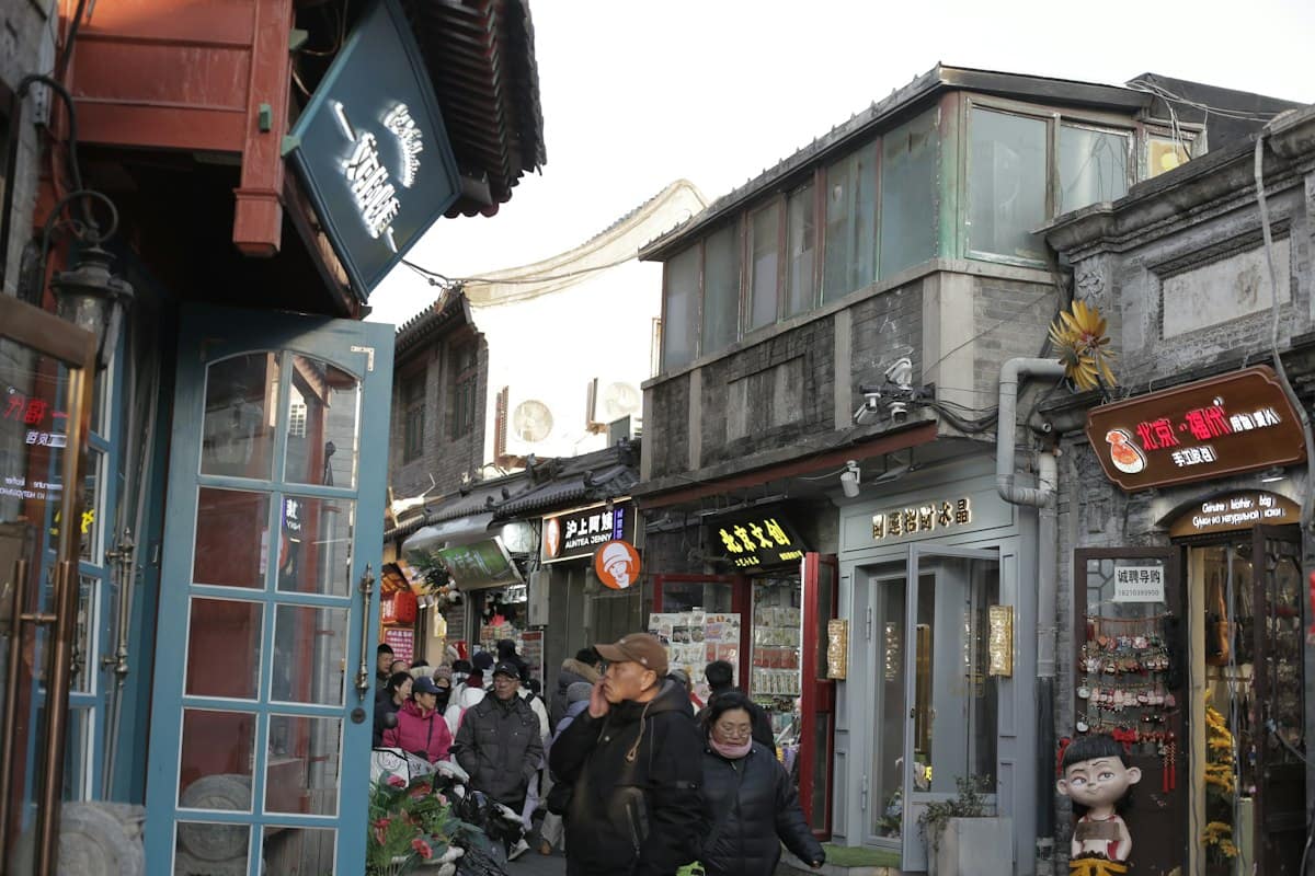 beijing hutongs - people walking down a narrow street lined with shops